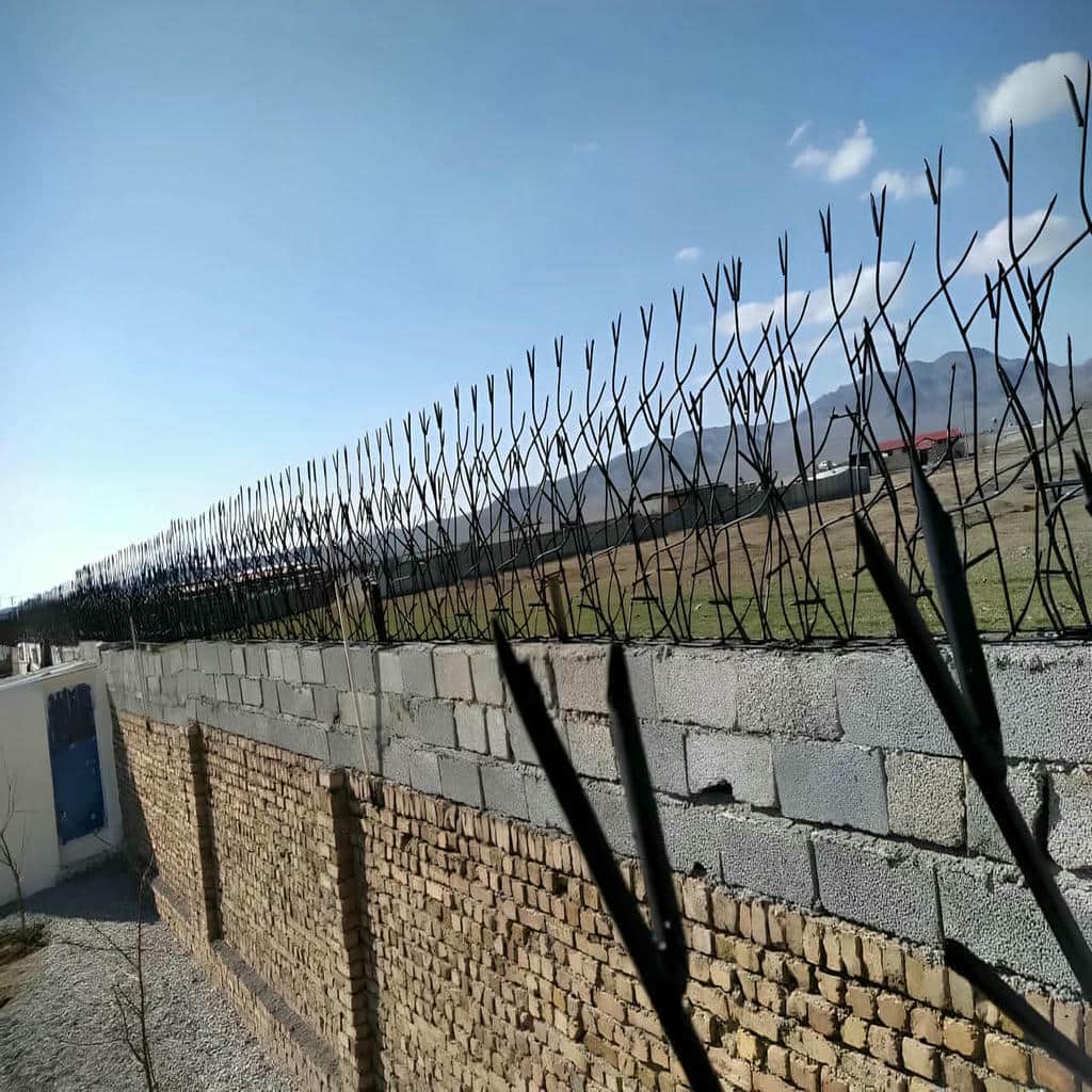 حفاظ سرنیزه ای فلزی کنار دیوار آجری حفاظ سرنیزه ای فلزی کنار دیوار آجری