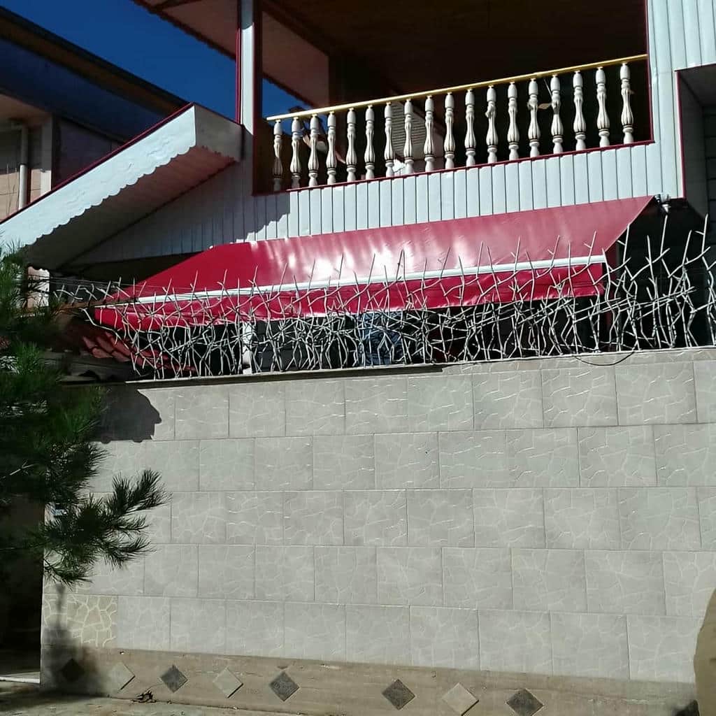 سایبان برقی بازویی با سازه تیره در نمای مغازه