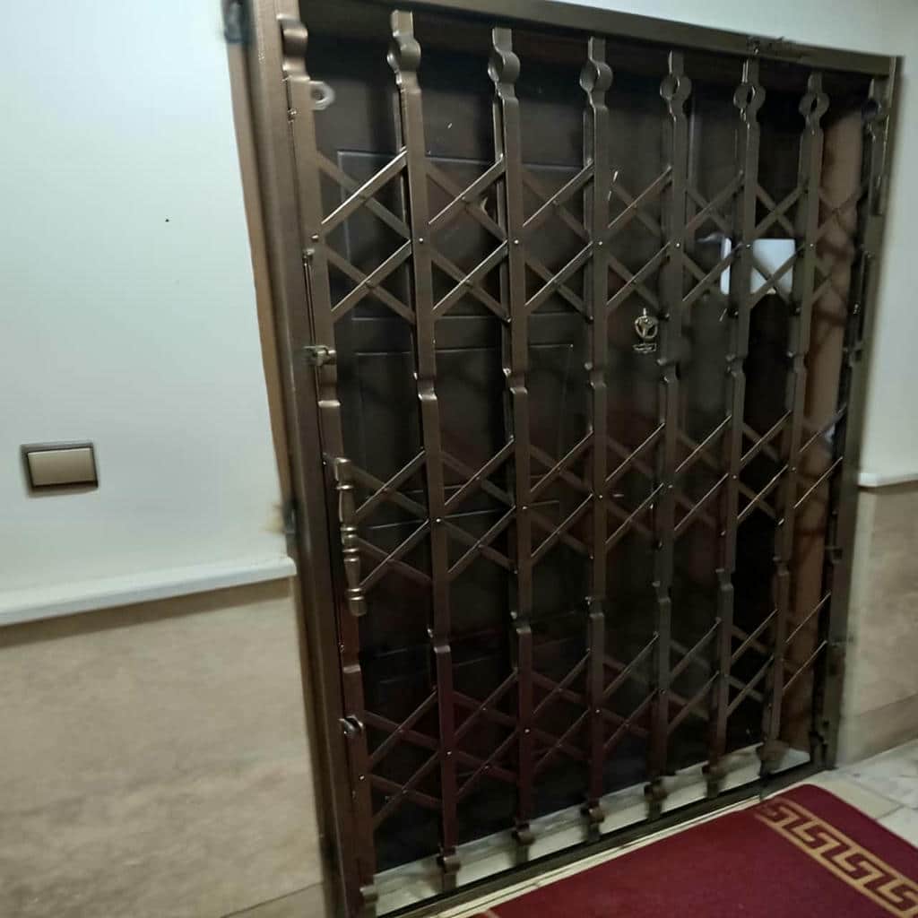 حفاظ درب آکاردئونی مشکی در ورودی آپارتمان استان خوزستان مرکز تخصصی فروش حفاظ درب آکاردئونی در استان خوزستان